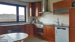 cocina con armarios de madera, mesa y ventana en Appartement mit Weitblick en Mönchengladbach