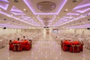 un gran salón de banquetes con mesas y sillas rojas y blancas en Grand Sydney Hotel en Batam Centre