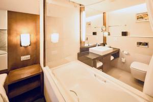 a bathroom with a tub and a sink and a toilet at Holiday Inn Qingdao City Center, an IHG Hotel - May 4th Square in Qingdao