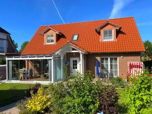 ボルテンハーゲンにあるFerienhaus Marinaの庭園付きの家屋のオレンジ色の屋根