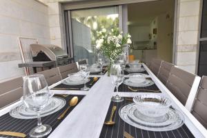 a long table with glasses and plates on it at דירת גן דלוקס-Deluxe Garden Apartment by CRWON in Eilat