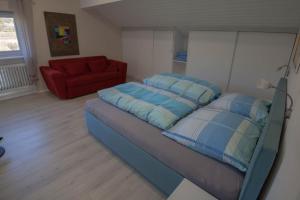 ein Schlafzimmer mit einem Bett und einem roten Sofa in der Unterkunft Ferienwohnung in Süddeutschland (D-CH-F) in Fischingen