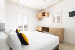 a white bedroom with a bed and a desk at Villa Fleur De Sel in Fanari