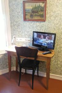 a desk with a computer on it with a television on it at Hotel & Cafe Lanterna in Nauvo +55 photos