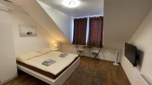 a small bedroom with a bed and a tv at CITY Apartman in Balatonföldvár