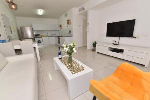 a white living room with a vase of flowers on a table at דירת גן דלוקס-Deluxe Garden Apartment by CRWON in Eilat