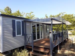 uma pequena casa com um alpendre e um deque em mobil home em Lacanau-Océan