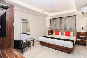 a bedroom with a bed and a chair and a television at Aarya Regency in Pune