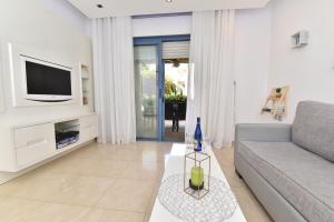 a living room with a couch and a tv at Royal Park Eilat - Garden Apartment by CROWN in Eilat