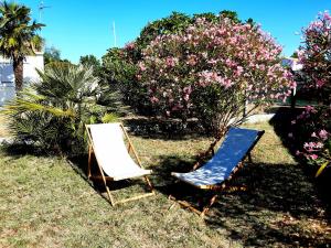 two chairs sitting in the grass next to some flowers at La Fleur des Marais - Maison tout confort au calme, grand jardin & balançoire in Le Château-dʼOléron +28 photos