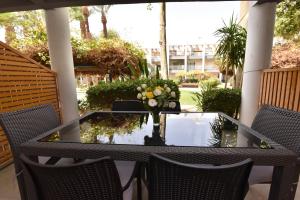 una mesa con un jarrón de flores en un patio en Royal Park Eilat - Garden Apartment by CROWN, en Eilat