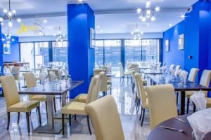 een eetkamer met tafels en stoelen en blauwe muren bij MERINA HOTEL in Yaoundé