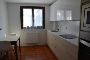 eine Küche mit einem Waschbecken, einem Tisch und einem Fenster in der Unterkunft Casa Miruetxe in Lekunberri