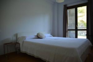 ein weißes Bett in einem Zimmer mit Fenster in der Unterkunft Casa Miruetxe in Lekunberri