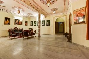 um quarto amplo com cadeiras e pinturas nas paredes em Hotel Radoli House - A Heritage Hotel em Jaipur