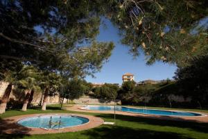 two swimming pools in a park with trees at Apartamentos Lomas De Campoamor in Dehesa de Campoamor