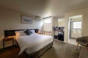 a bedroom with a large white bed and a chair at Georges Bay Apartments in St Helens