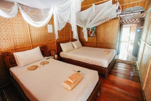 two beds in a room with white sheets at River Kwai Jungle Rafts - SHA Extra Plus in Sai Yok