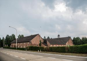 un edificio de ladrillo con una torre de reloj a un lado de una carretera en Craywinckelhof Streekbelevingscentrum, en Lubbeek