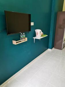 eine blaue Wand mit einem Flachbild-TV und einer Vase in der Unterkunft VILLA SENTOSA in Kuala Terengganu