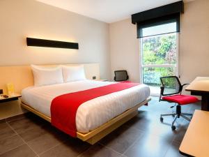 1 dormitorio con 1 cama grande y 1 silla roja en City Express Plus by Marriott Cali Colombia, en Cali