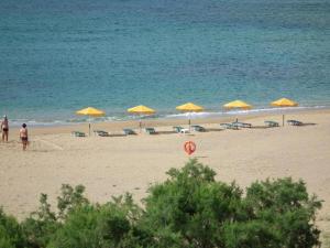 a beach with yellow umbrellas and chairs and the ocean at Gramvoussa Bay in Kissamos