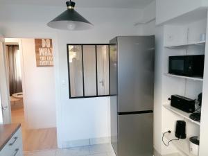 a kitchen with a stainless steel refrigerator in a room at SWEET Appartment avec Wifi et parking in Clermont-Ferrand
