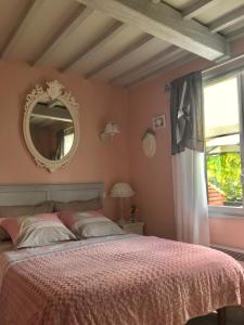 a bedroom with a bed with a mirror and a window at Les Chambres de Paule in Thieulloy-lʼAbbaye