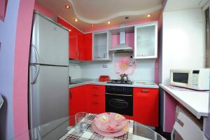 uma cozinha com armários vermelhos e uma mesa de vidro em Однокомнатная посуточно на Жукова 148Б em Omsk