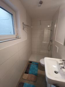 a white bathroom with a sink and a shower at Kinderlachen in Wasserburg am Bodensee