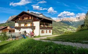 a house on a hill with mountains in the background at Grödnerhof Heidi in Brie