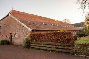 a red brick building with a brown roof at Wiemannshof 25191 in Bunde