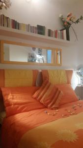 1 dormitorio con 1 cama con sábanas de color naranja y libros en Acero Rosso B&B apartment, en San Lazzaro di Savena