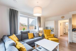 uma sala de estar com um sofá azul e cadeiras amarelas em Haus Hein Mück em Norddeich
