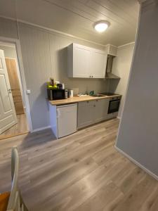 a kitchen with white cabinets and a wooden floor at Mosjøen Overnatting, Vollanvegen 13 in Mosjøen