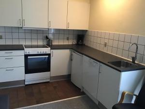 a kitchen with white cabinets and a sink at Løkken Badehotel Apartments in Løkken