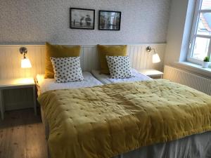 a bedroom with a large yellow bed with two pillows at Løkken Badehotel Apartments in Løkken