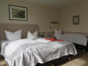 a bedroom with two beds with white sheets and a red flower on the bed at Der Landhof Sanddorn in Stolpe