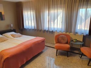 um quarto de hotel com uma cama, uma cadeira e janelas em Hotel Maurice em Nieuwvliet