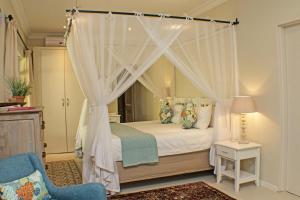 a bedroom with a canopy bed with a blue chair at Khaya Ndlovu Safari Manor in Hoedspruit