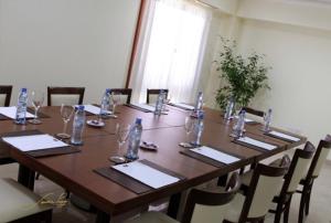 una larga mesa de madera con sillas y vasos. en Grand Hotel Libertad en Nueve de Julio