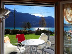 eine Terrasse mit einem Tisch und Stühlen sowie Blick auf das Wasser in der Unterkunft Apartment Am Brienzersee by Interhome in Brienz