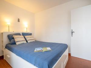 een slaapkamer met een blauw bed met twee boeken erop bij Holiday Home Grau Village by Interhome in Le Grau-du-Roi