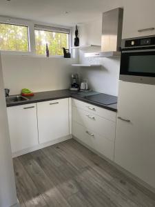 uma cozinha com armários brancos e um lavatório em KASITA12 em Domburg