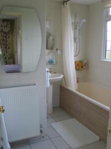 een badkamer met een bad, een wastafel en een spiegel bij The Beeches Bed and Breakfast in Hinckley