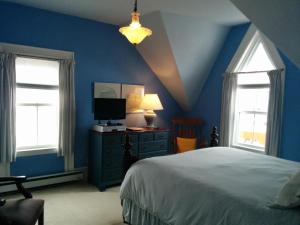 a blue bedroom with a bed and two windows at Fairmont House Bed & Breakfast in Mahone Bay