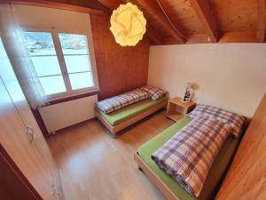 een zolderkamer met 2 bedden en een raam bij Apartment Casa Milu by Interhome in Engelberg