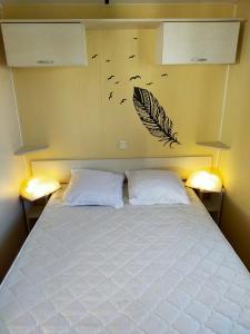 a bedroom with a bed with two pillows and birds on the wall at Camping Cap Soleil île d'Oléron 4 étoiles in La Bétaudière
