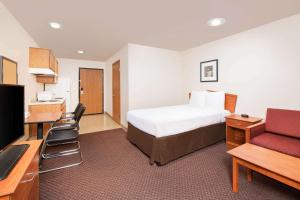 ein Hotelzimmer mit einem Bett und einem Schreibtisch in der Unterkunft WoodSpring Suites Columbus Fort Moore in Columbus