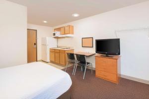 ein Hotelzimmer mit einem Bett und einem Flachbild-TV in der Unterkunft WoodSpring Suites Columbus Fort Moore in Columbus